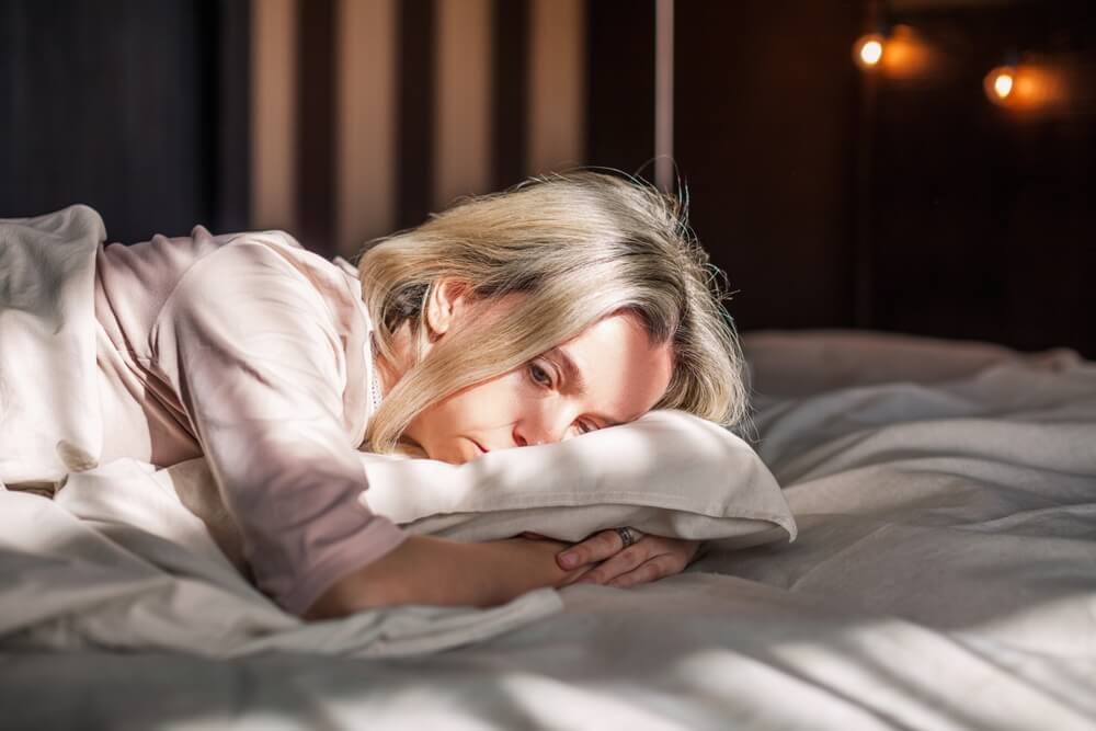 Tired middle aged woman lying in bed can't sleep late at morning with insomnia